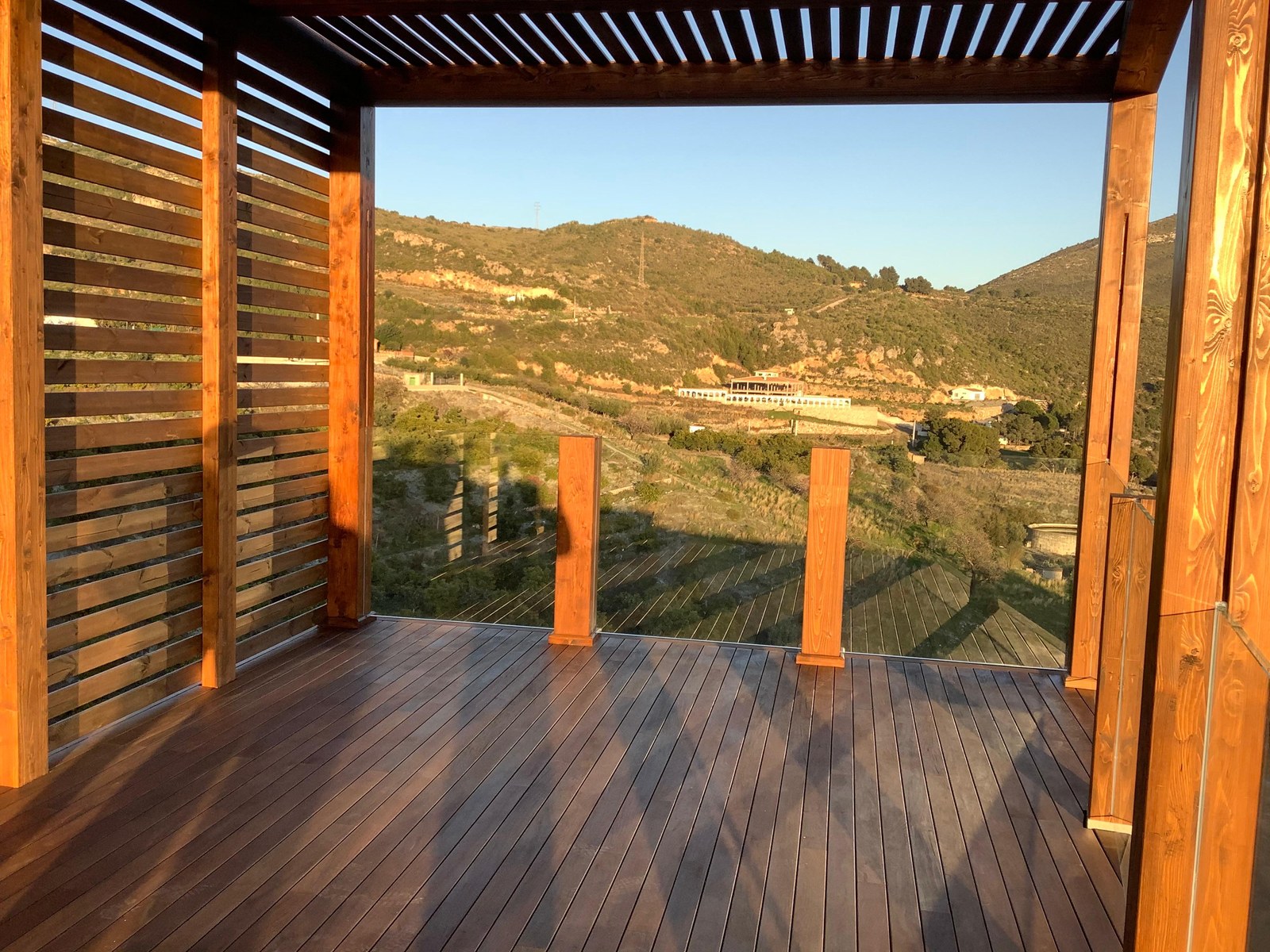 Terraza con tarima de madera y pérgola con vistas a la montaña