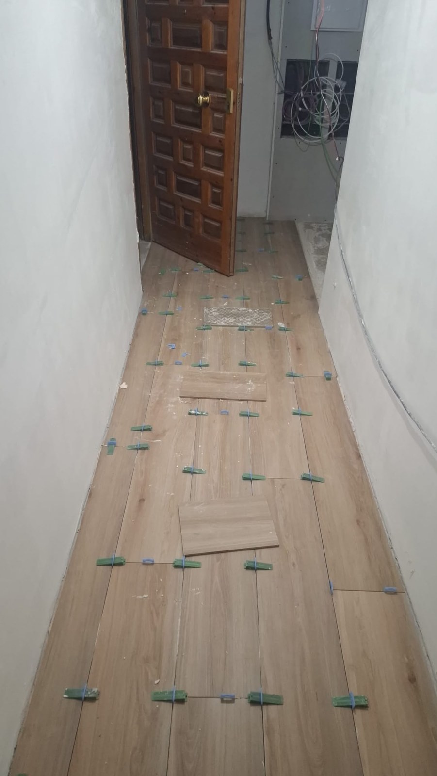 Colocación de suelo porcelánico efecto madera con niveladores en el pasillo