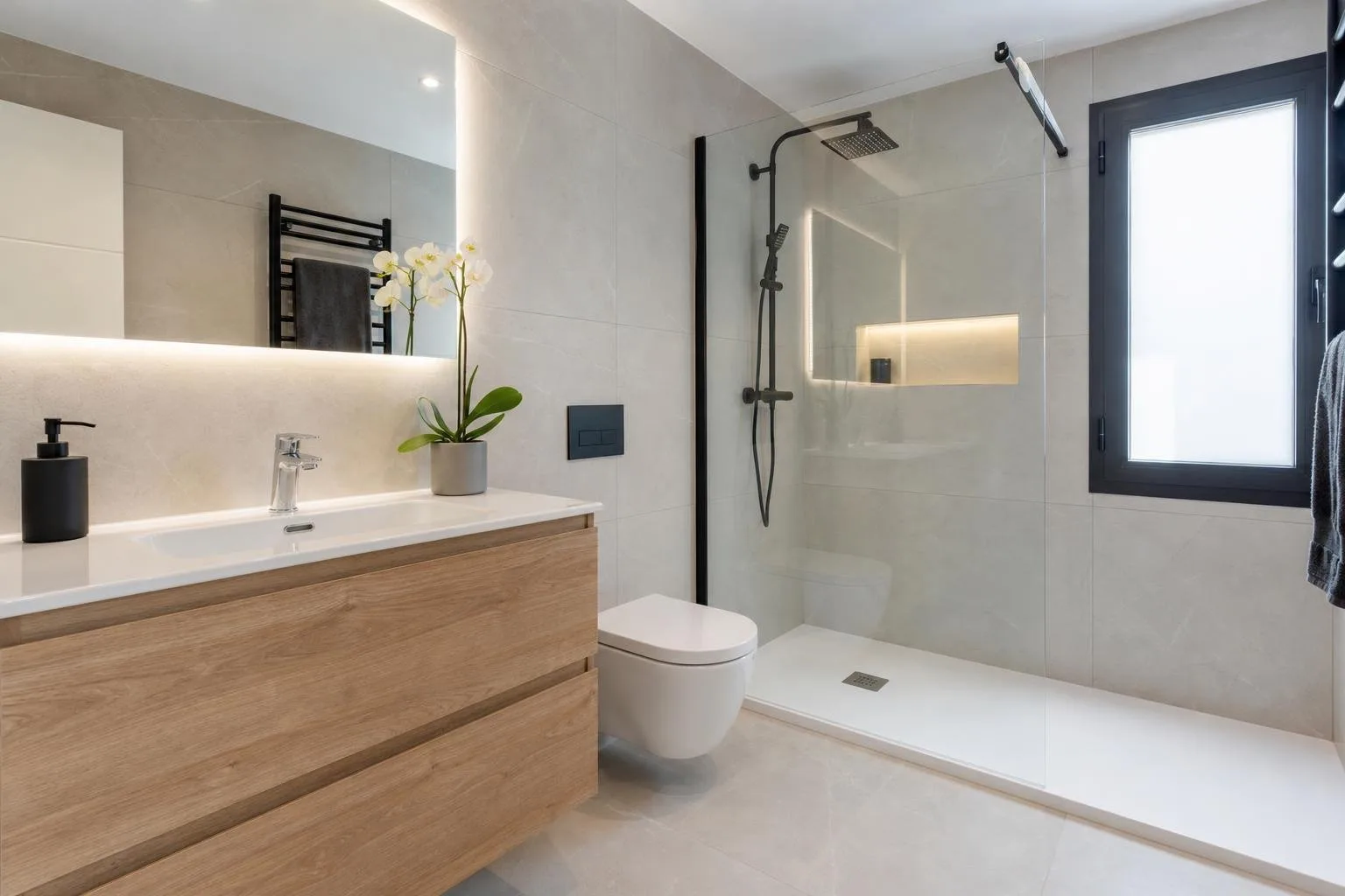 Baño terminado con ducha de obra, mampara de vidrio y mueble de madera