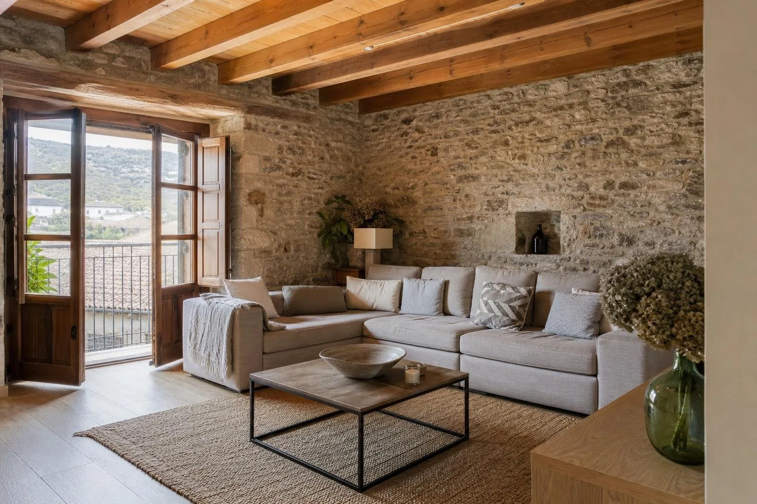 Salón de casa de pueblo reformada con pared de piedra y vigas de madera