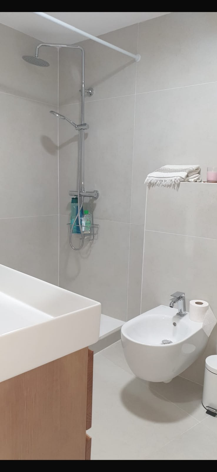 Baño con ducha de obra, rociador de techo y sanitarios suspendidos