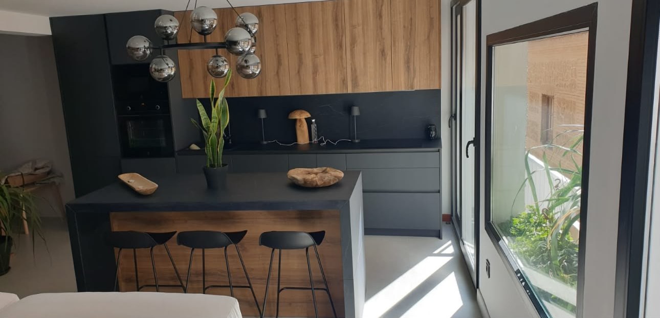 Cocina negra y madera con isla y lámpara de bolas