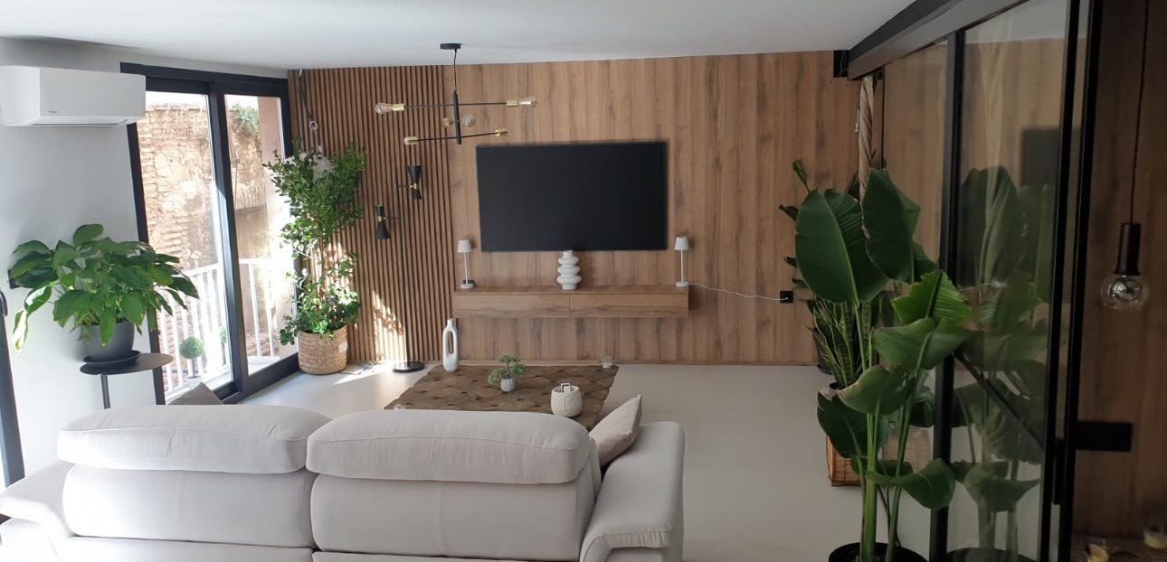 Salón con pared de listones de madera y mueble de televisión volado