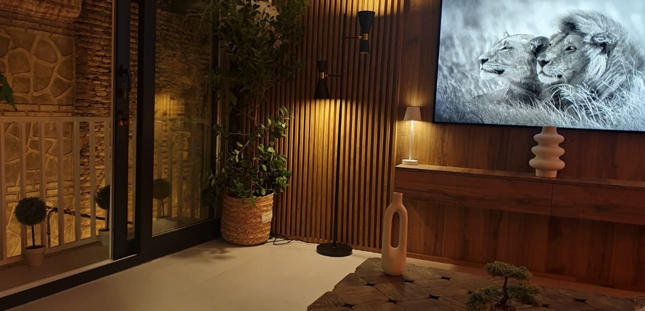 Rincón del salón con revestimiento de listones de madera y luz indirecta