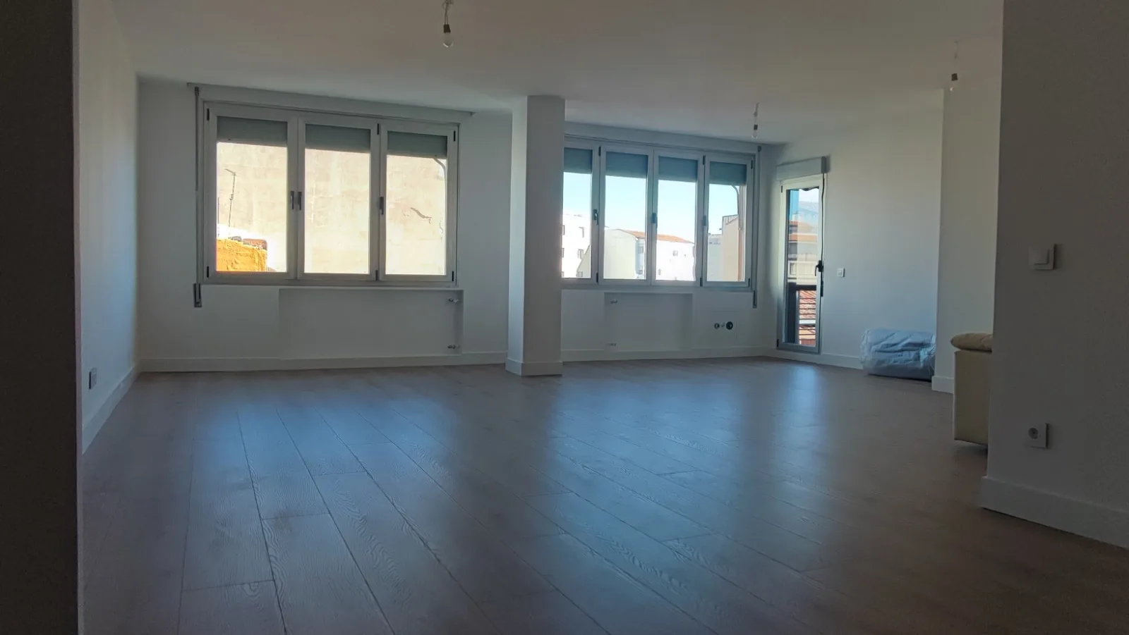 Salón amplio de un piso reformado con suelo laminado y ventanas luminosas