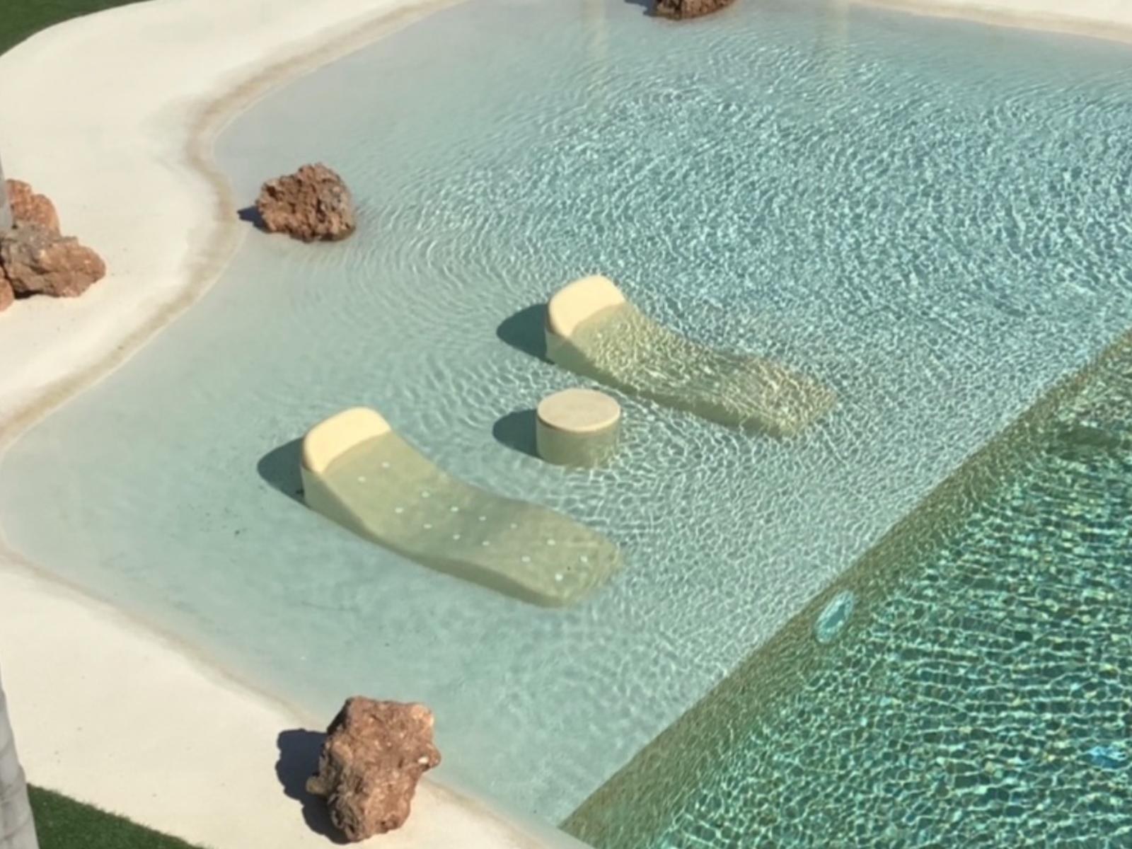 Zona de baño de la piscina con tumbonas integradas