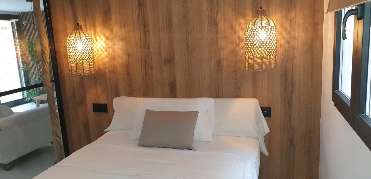 Dormitorio con cabecero de madera y lámparas colgantes